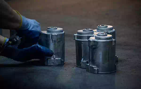 Mano con guanto effettua lavoro di sbavatura manuale.